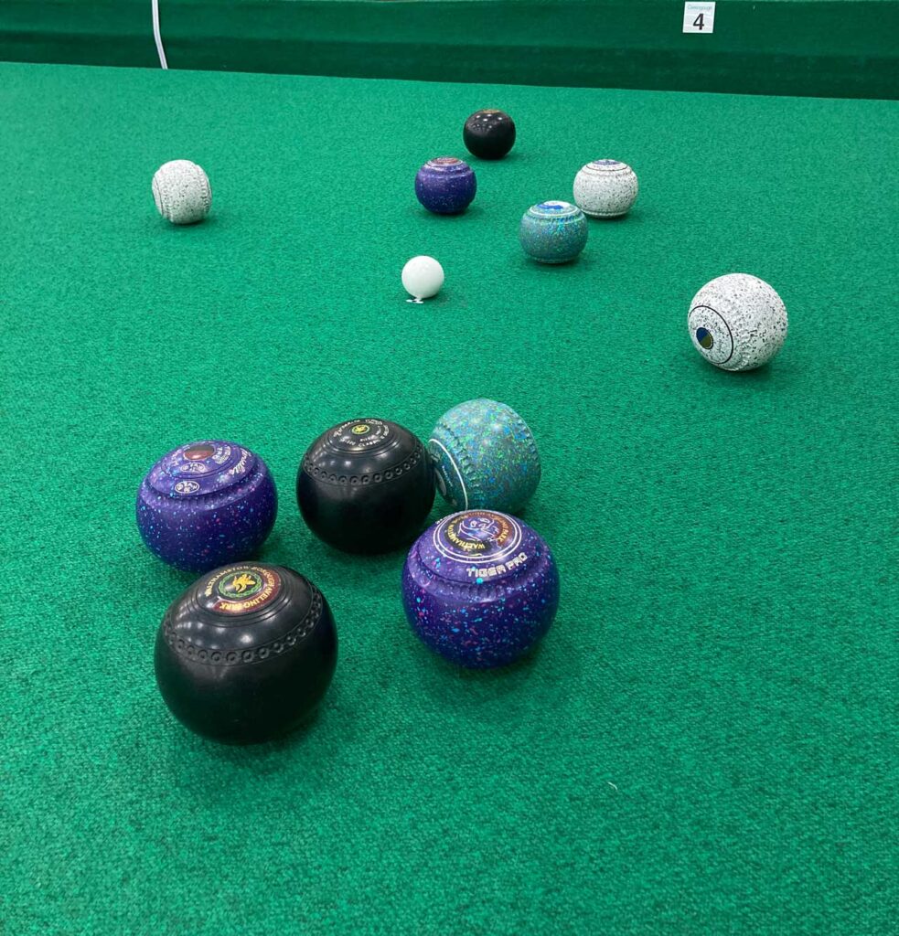 A head of green, white, purple and black bowls, with the green bowl closest to the jack