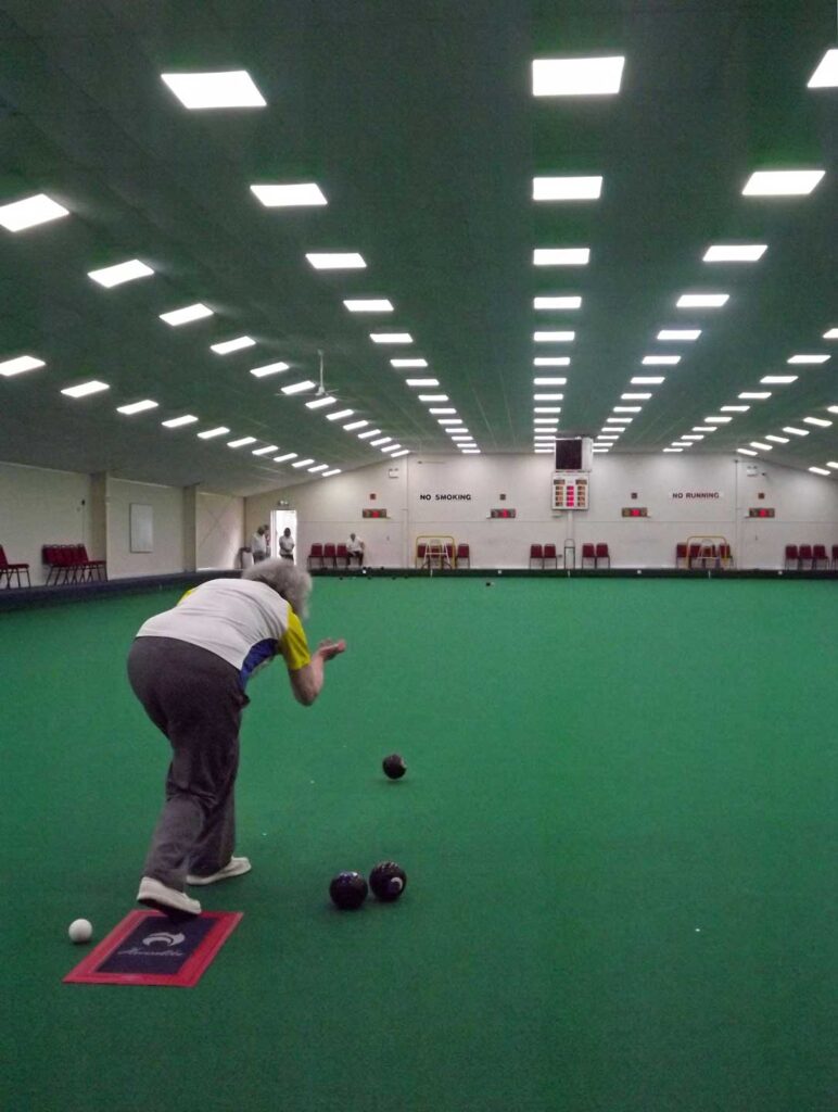 A woman delivering a bowling ball down an empty green